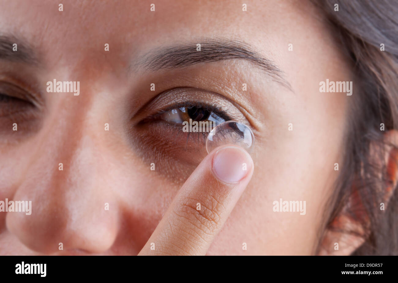 Vista di una donna occhio marrone durante l'inserimento di una lente a contatto Foto Stock