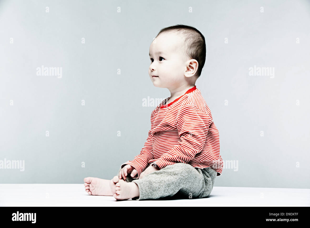 Ritratto di baby boy indossare top a strisce che guarda lontano Foto Stock