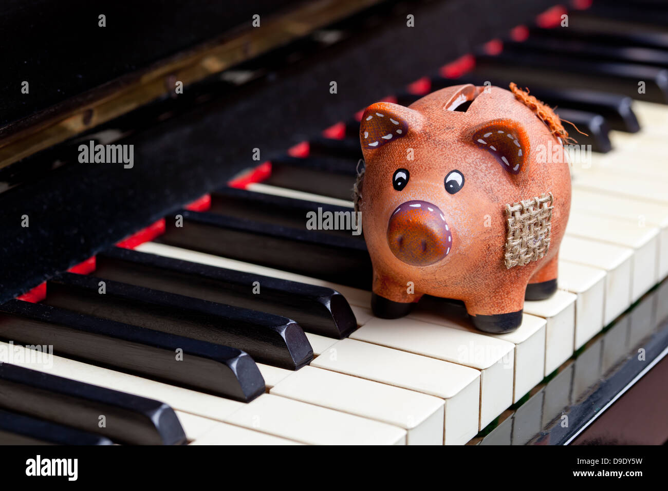 La musica e il concetto di risparmio con il pianoforte e il salvadanaio Foto Stock