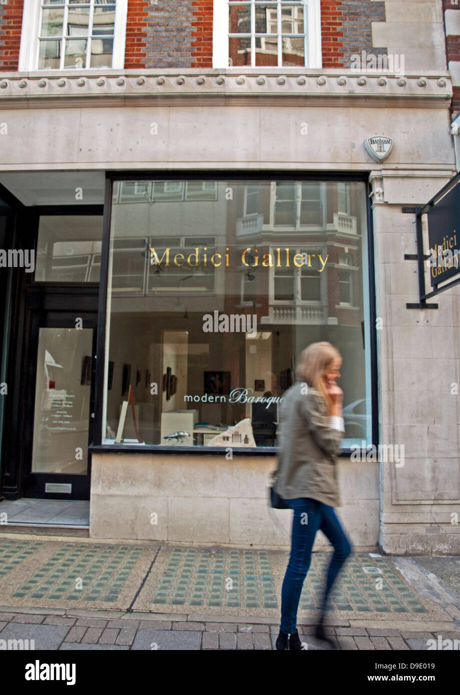 Femmina su telefono cellulare a camminare lungo la galleria dei Medici su Cork Street,una delle più famose strade per le gallerie d'arte a Londra Foto Stock