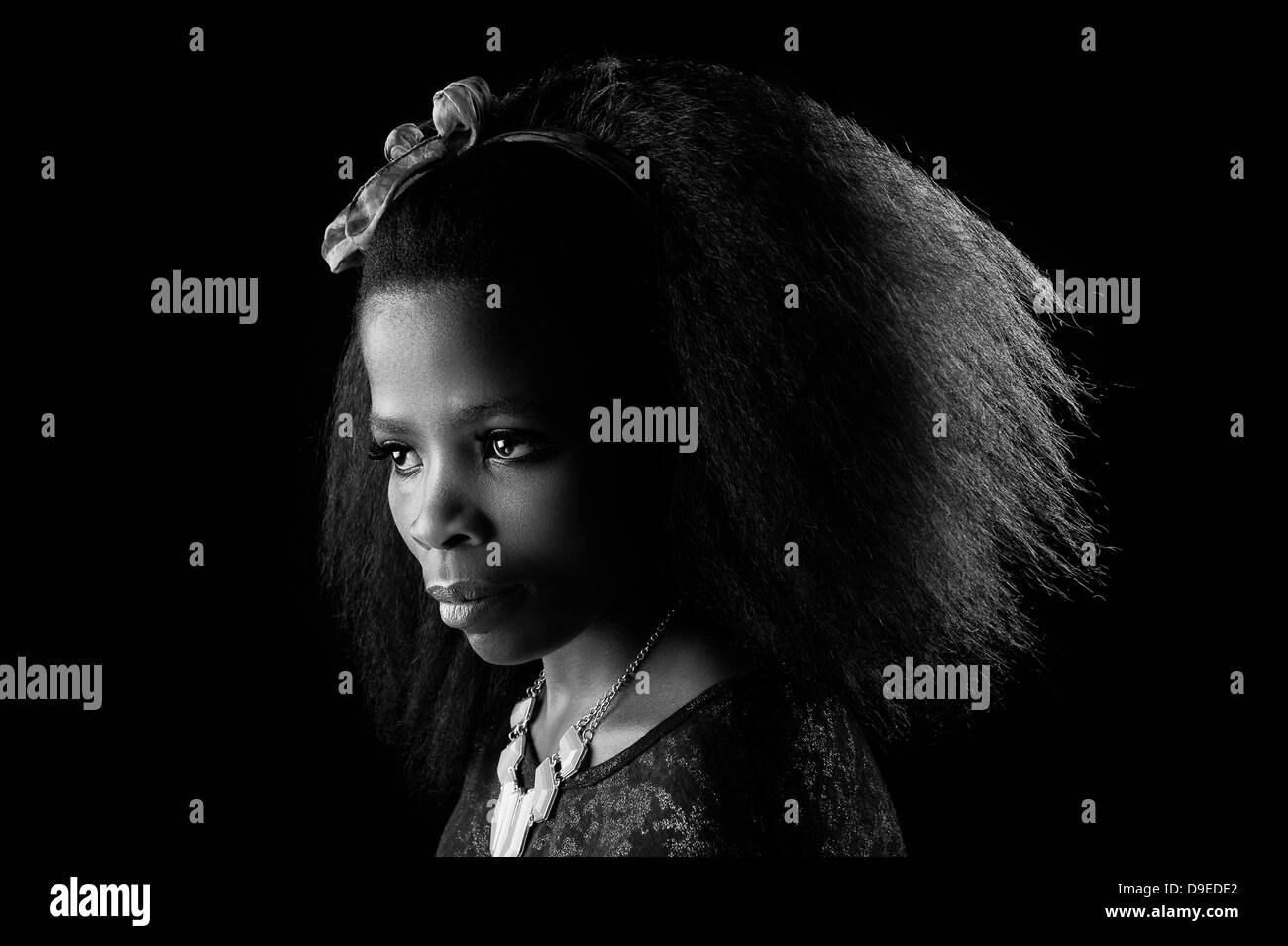 Giovane donna africana con bellissimi capelli afro, una chiave di basso, sfondo bianco & nero studio shot. Drammatica espressione del viso. Foto Stock