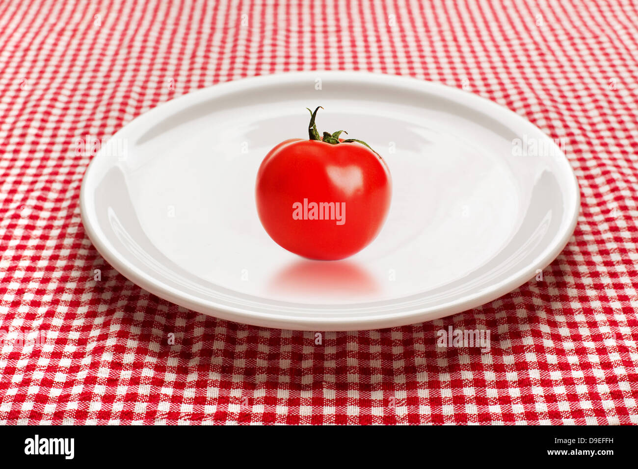 Rosso Pomodoro su una piastra bianca sul tavolo da cucina. Cibo organico e concetto di dieta. Foto Stock