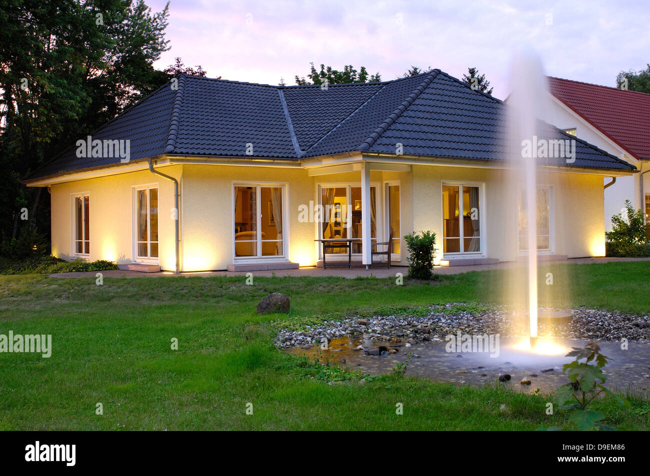 Casa con le luci della sera giardino Foto Stock
