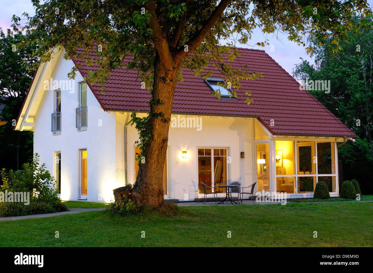 Casa con le luci della sera giardino Foto Stock