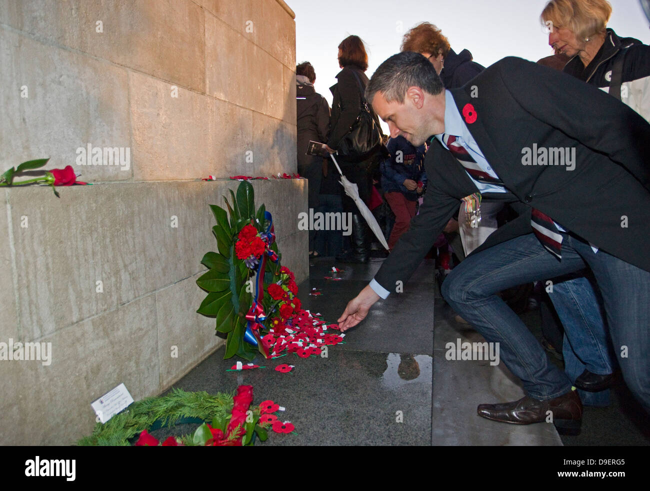 Un uomo stabilisce un papavero all'Anzac GIORNO Dawn, servizio War Memorial Museum, Auckland, Nuova Zelanda Foto Stock