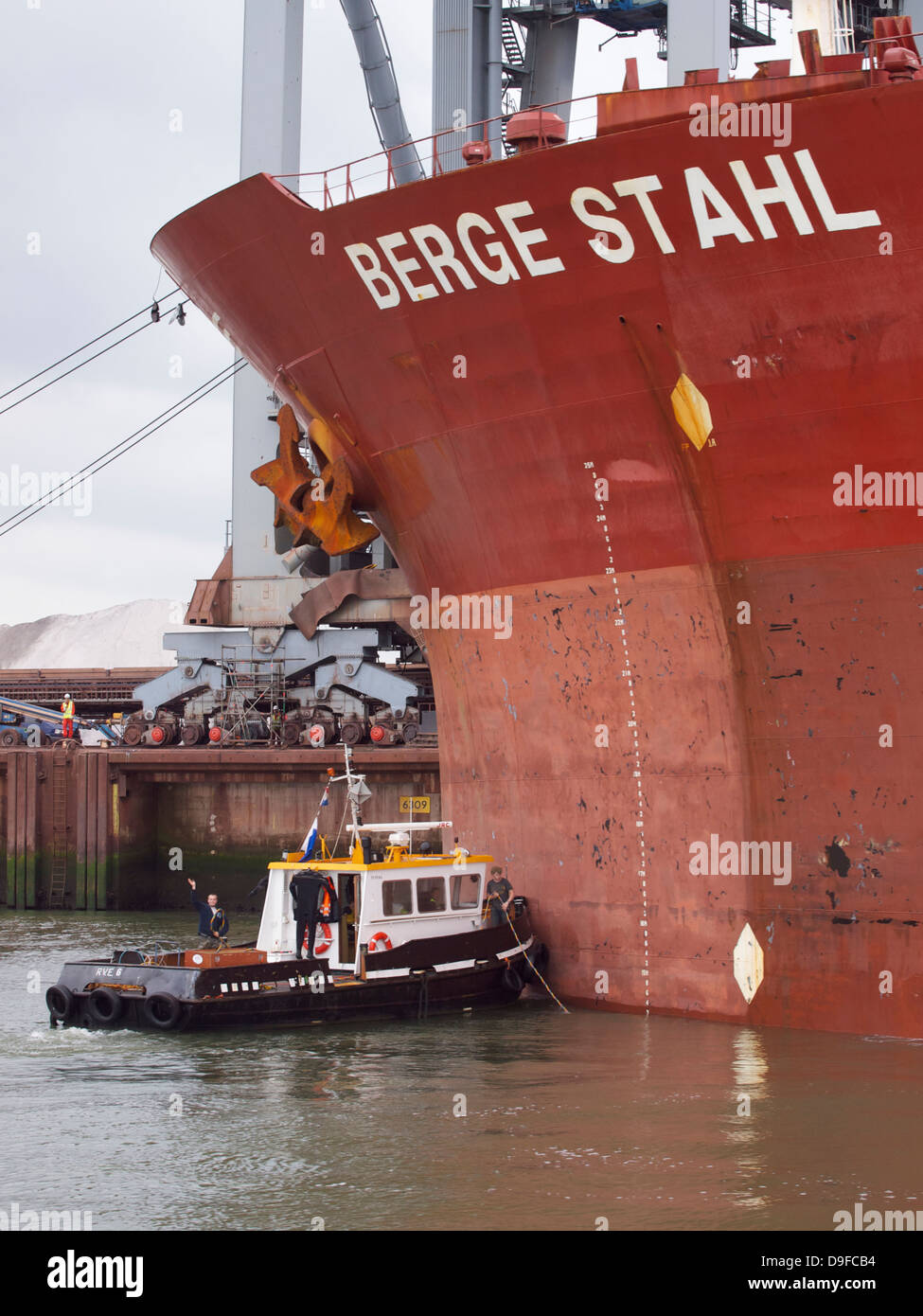 Gli uomini sulla loro piccola barca e preparare il lavoro sulla Berge Stahl una delle più grandi navi portarinfuse in tutto il mondo. Porto di Rotterdam Foto Stock