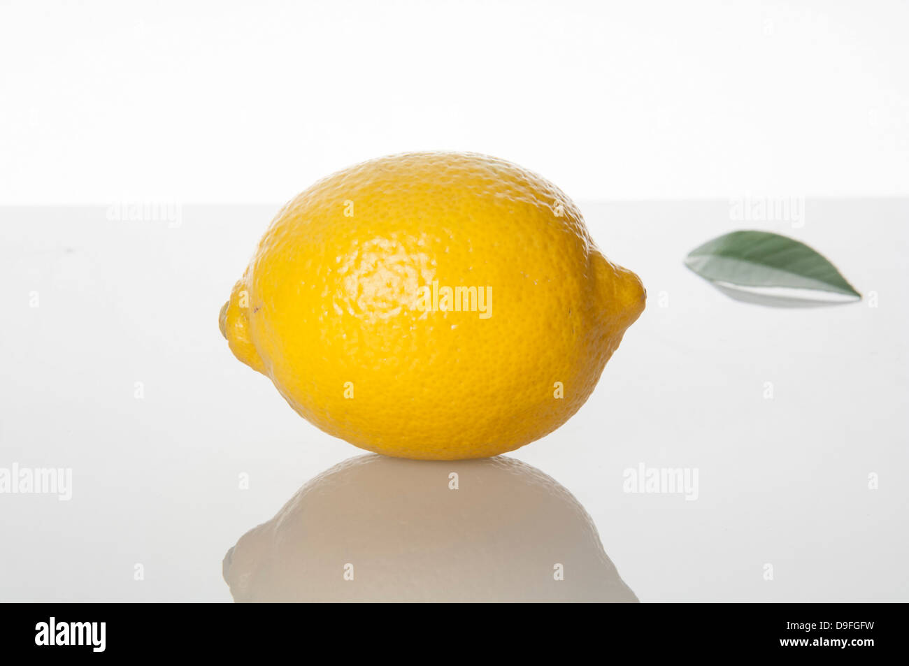 Un limone sul bianco con foglia di limone Foto Stock