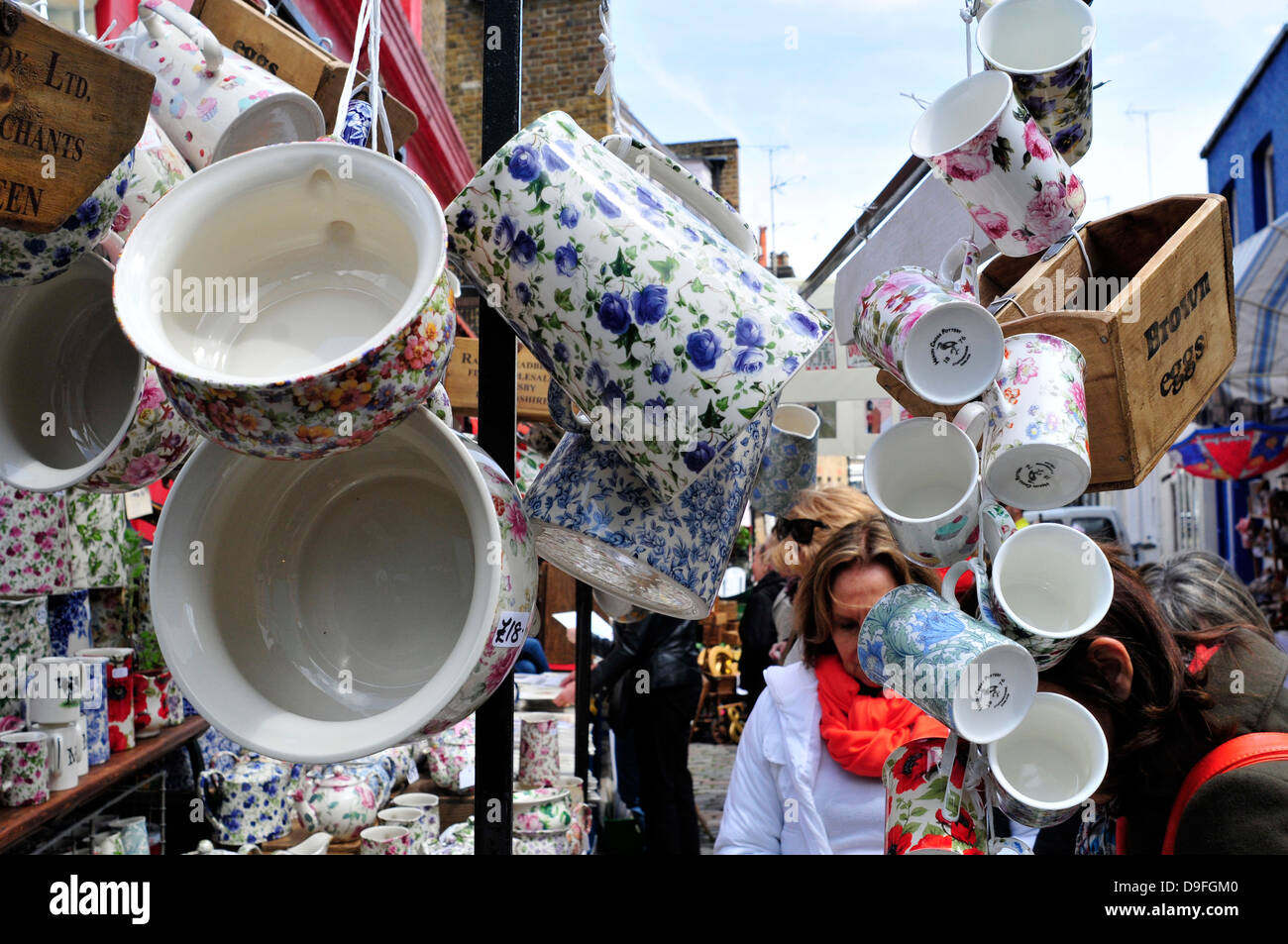 Una donna navigando in un negozio di antiquariato, Mercato di Portobello Road, Londra, Regno Unito. Foto Stock