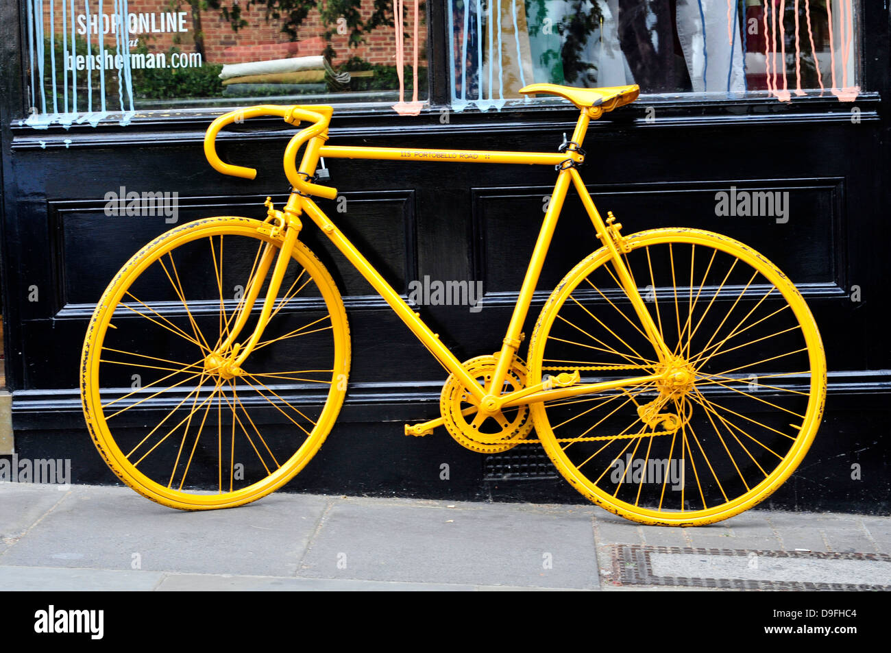 Un giallo bicicletta appoggiata contro un negozio, Portobello Road, London, Regno Unito " Foto Stock