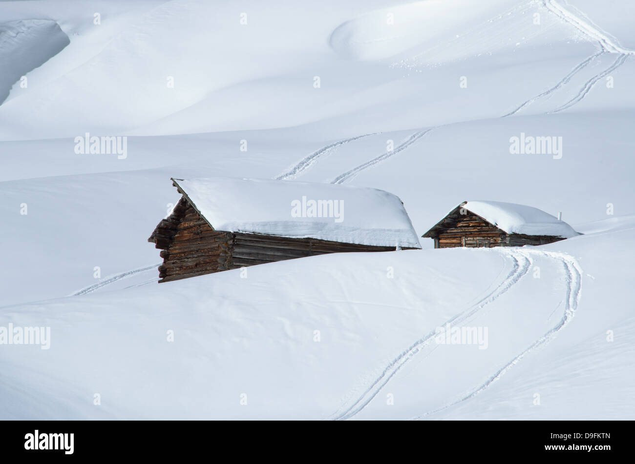 Due vecchi fienili in legno circondato da profondi neve e piste da sci nelle Dolomiti, Alto Adige, Italia Foto Stock