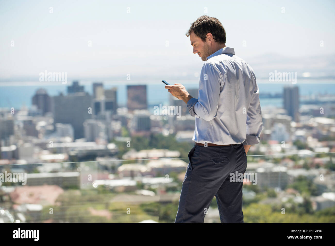 Uomo in piedi sulla terrazza con un telefono cellulare Foto Stock