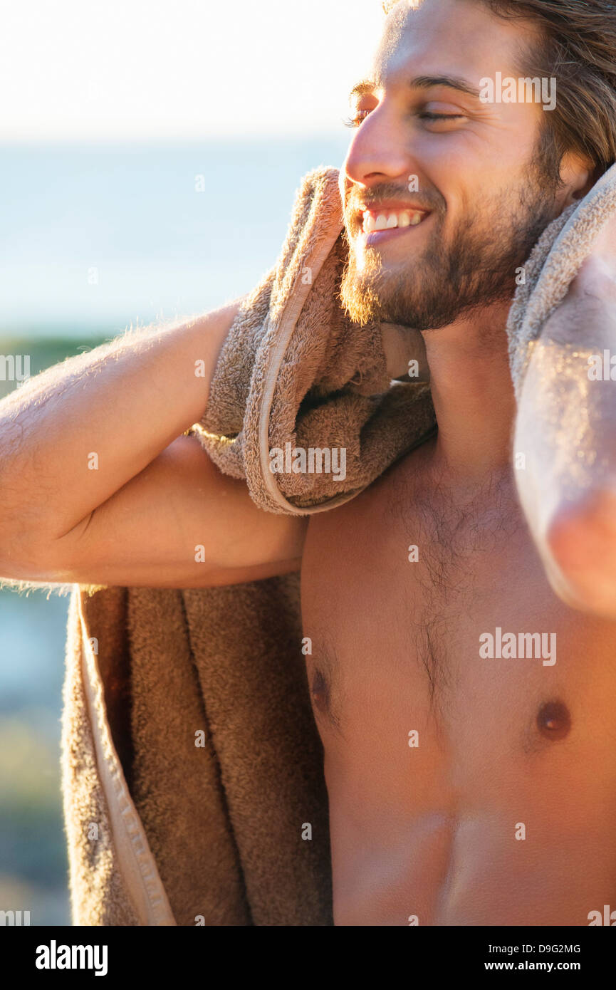 Felice l'uomo stesso di strofinamento con un panno sulla spiaggia Foto Stock