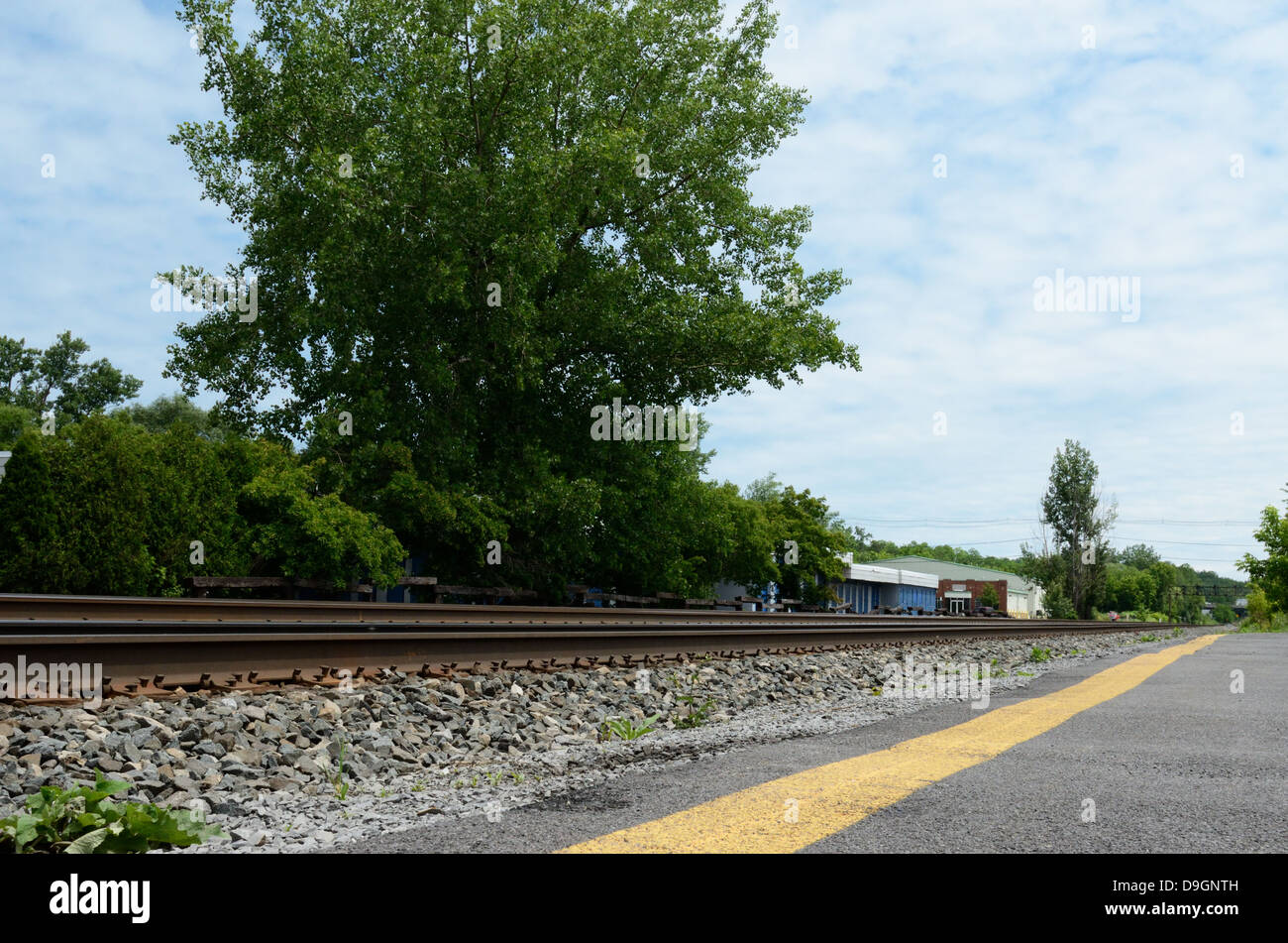 I binari della ferrovia con auto parcheggio nei pressi di intersezione stradale. Foto Stock