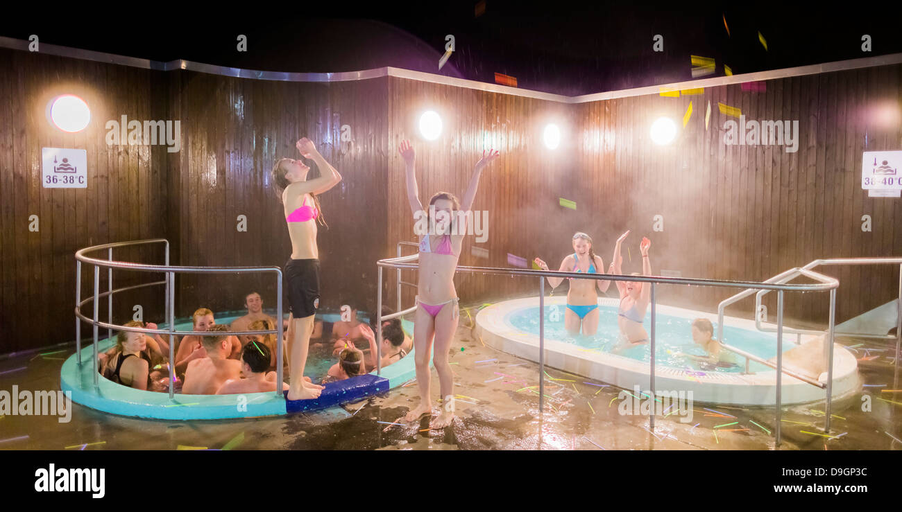 Le persone che si godono la vasca con acqua calda in uno dei tanti geotermica piscine riscaldate a Reykjavik, Islanda Foto Stock