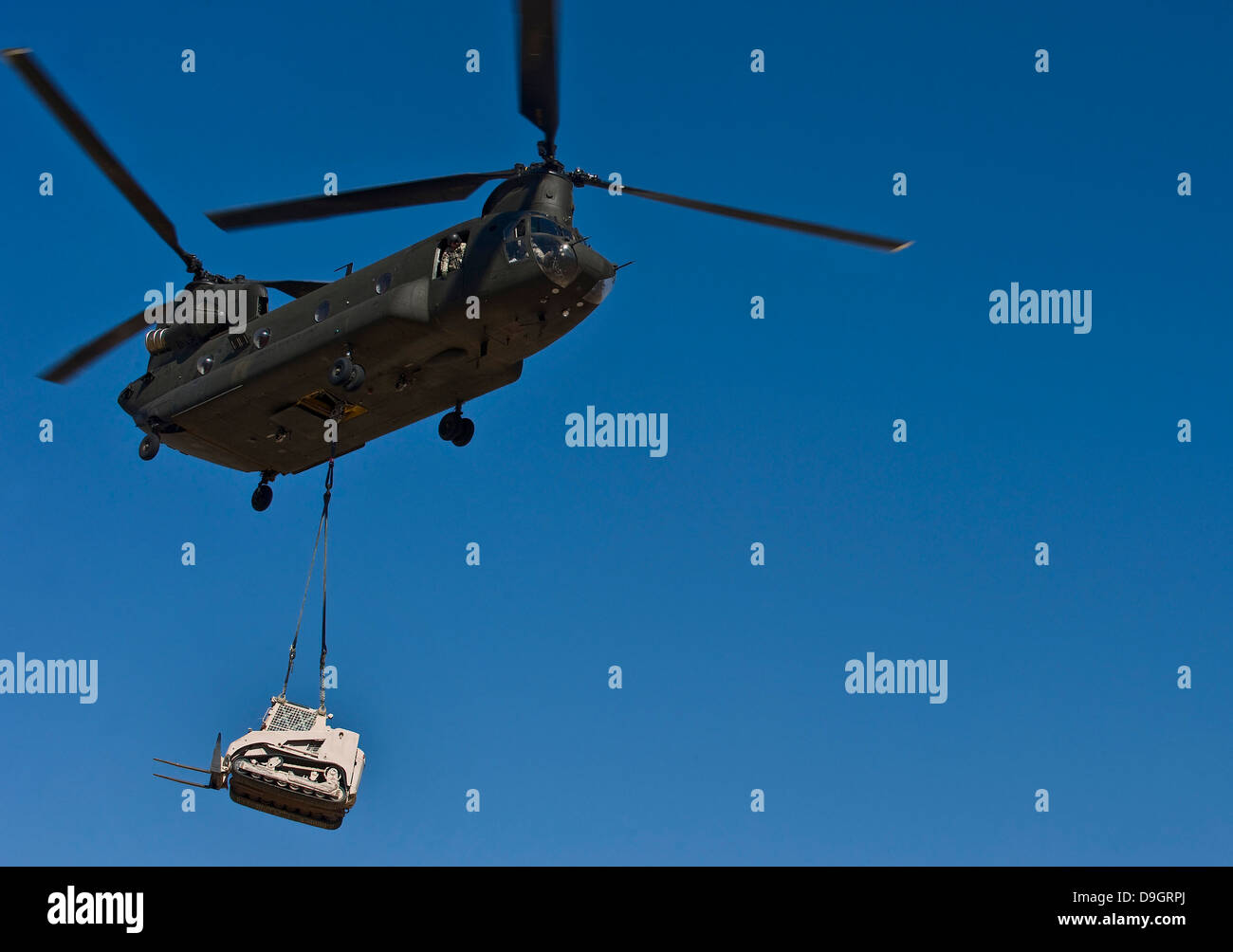 Un U.S. Esercito CH-47 Chinook porta un bulldozer per un sito di caduta. Foto Stock