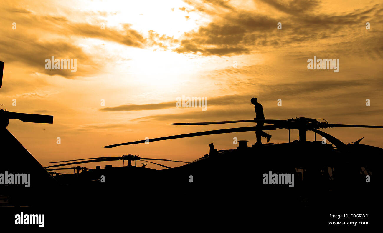 2 maggio 2012 - un pilota conduce una ispezione pre-volo su un UH-60 Black Hawk elicottero come il sole sorge. Foto Stock