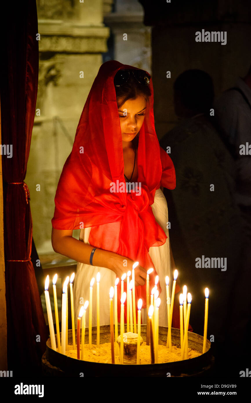 Donna accendere una candela alla chiesa del Santo Sepolcro nella città vecchia di Gerusalemme, Israele. Foto Stock