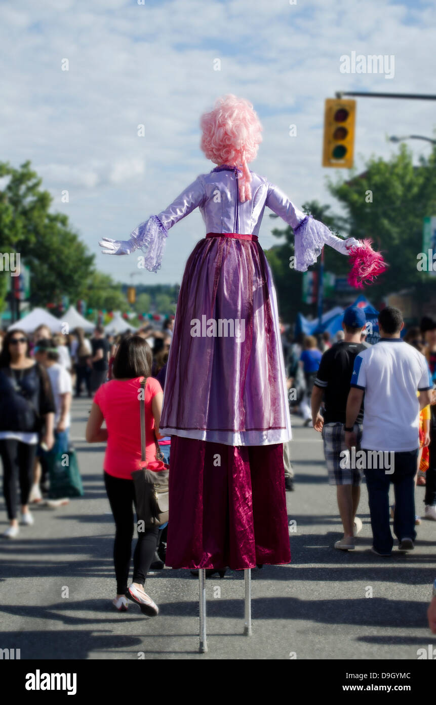 Colorato costume femminile performer passeggiate su palafitte tra la folla della Giornata italiana street festival di Vancouver, BC Canada. Foto Stock