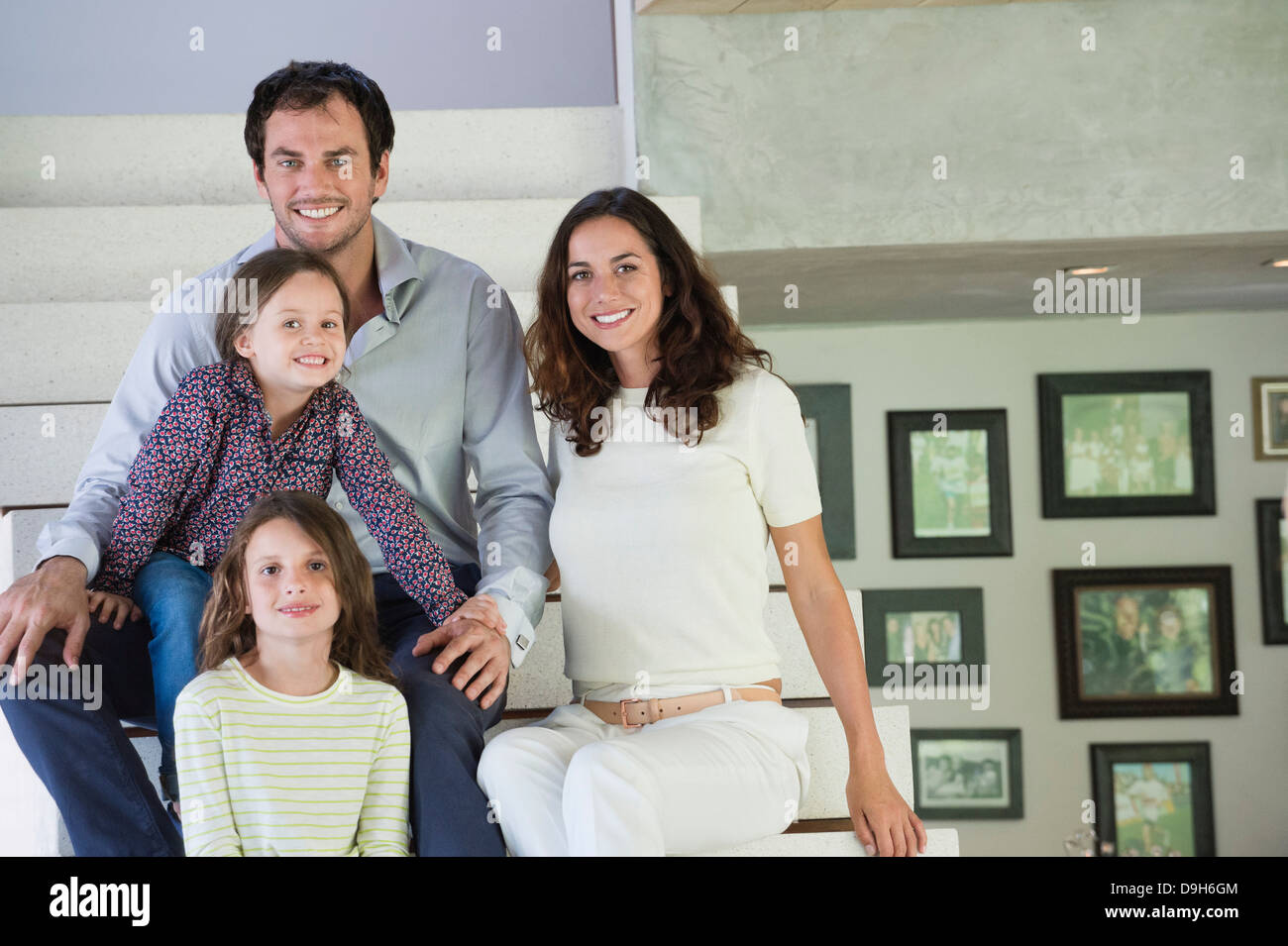 Famiglia seduti sui gradini e sorridente Foto Stock