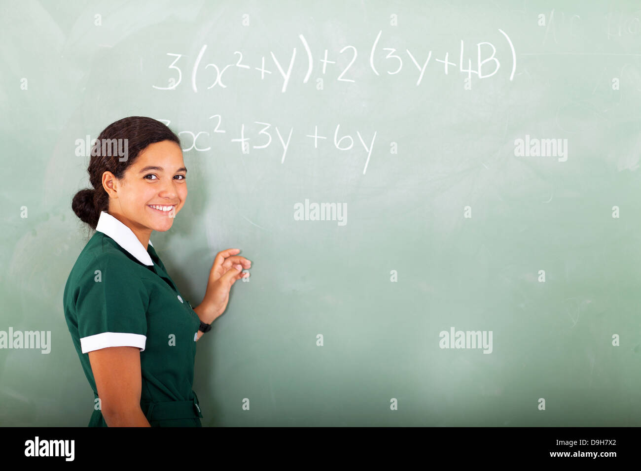 Felice giovani nella scuola media facendo matematica sulla lavagna Foto Stock