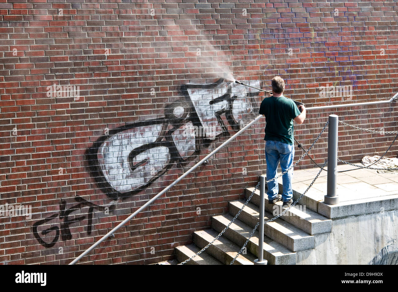L'uomo elimina graffiti da un muro, rimosso graffiti su un flusso, Foto Stock