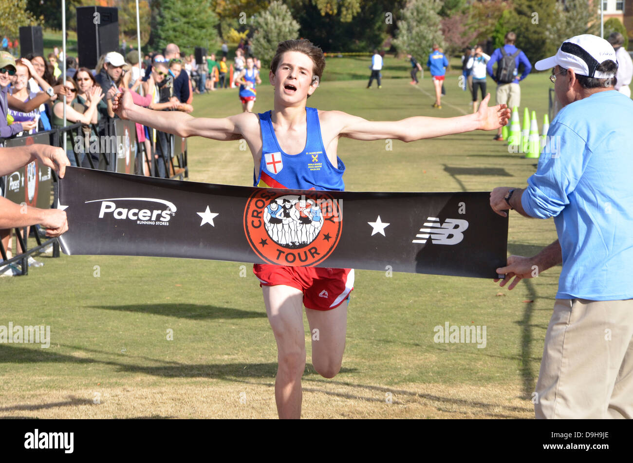 Adolescente attraversa la linea del traguardo dopo una corsa in una scuola di cross country match Foto Stock