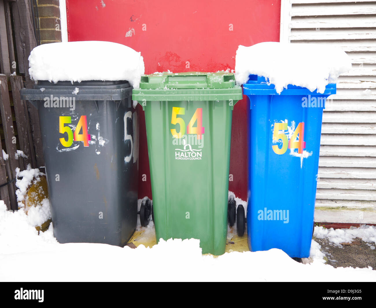 Scomparti wheelie fuori dalla casa, coperto di neve. Nero, Verde e contenitori blu. Foto Stock