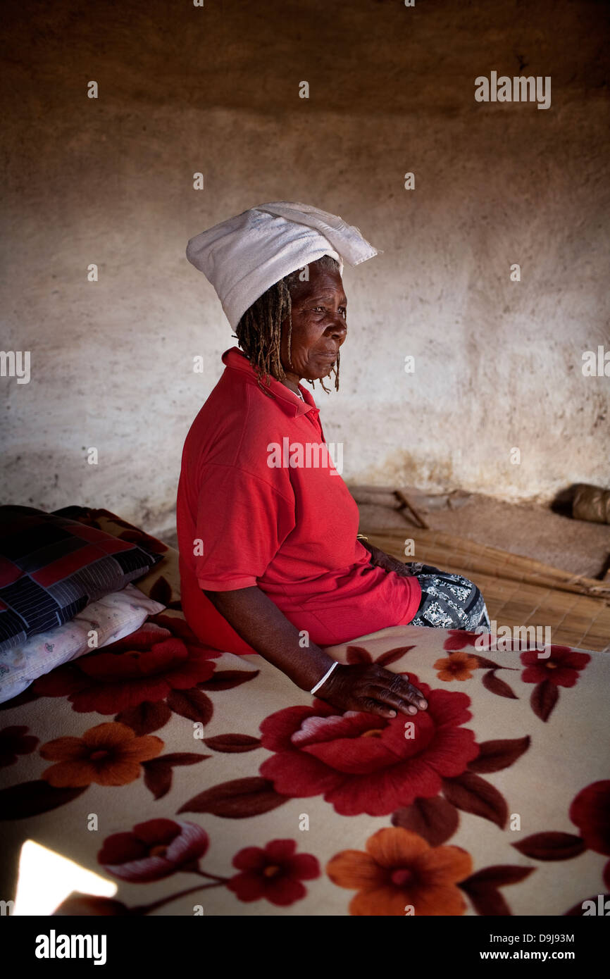 Sangoma donna si siede sul suo letto di casa in rural Transkei, Sud Africa Foto Stock