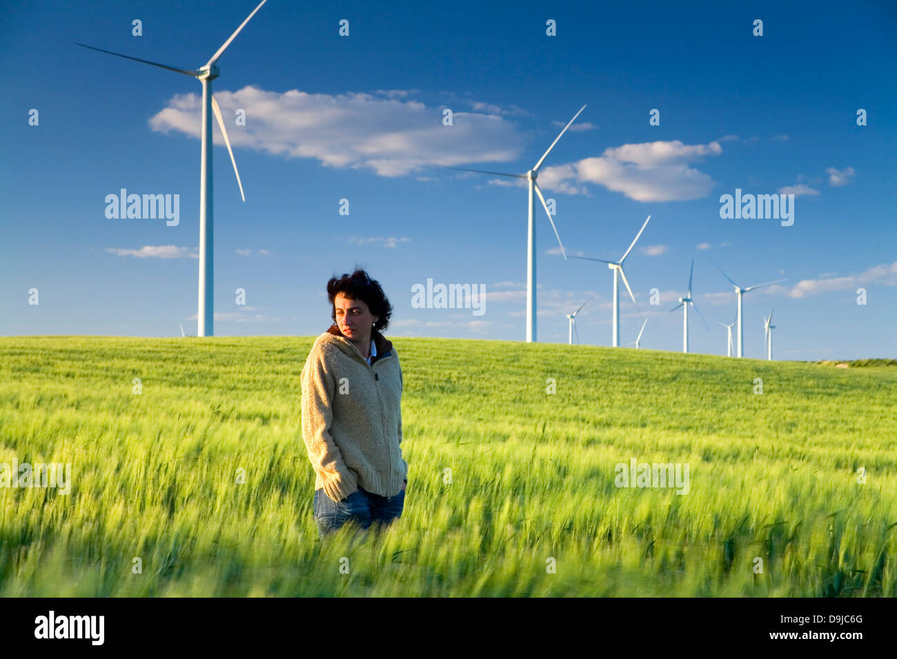 Una giovane donna in una turbina eolica stazione in un campo. Sanlucar de Barrameda, Cadice, Andalusia, Spagna, Europa. Foto Stock