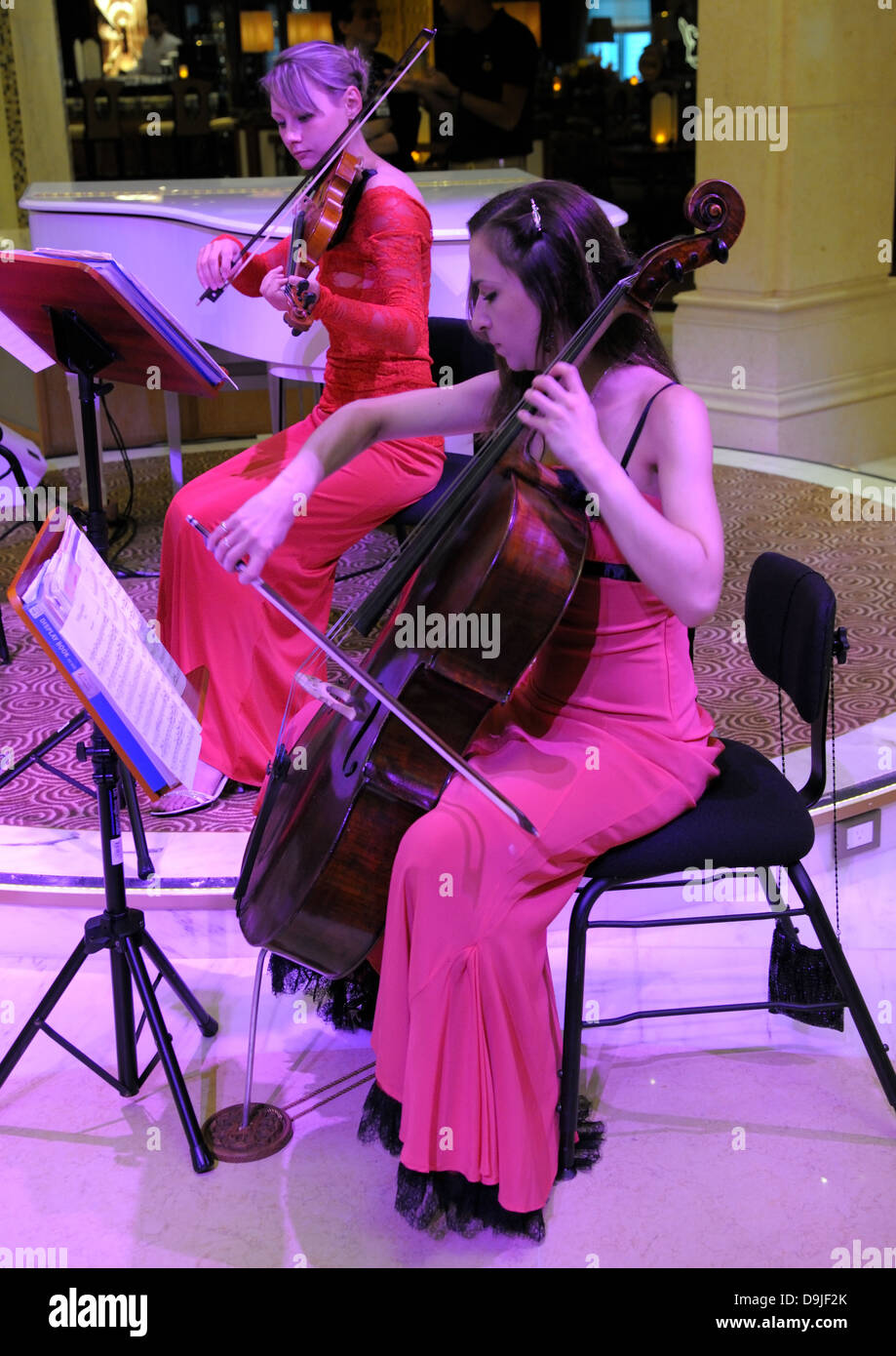 Signora musicisti suonano. Profondo rosso abiti e moody magenta illuminazione su argomenti. Foto Stock