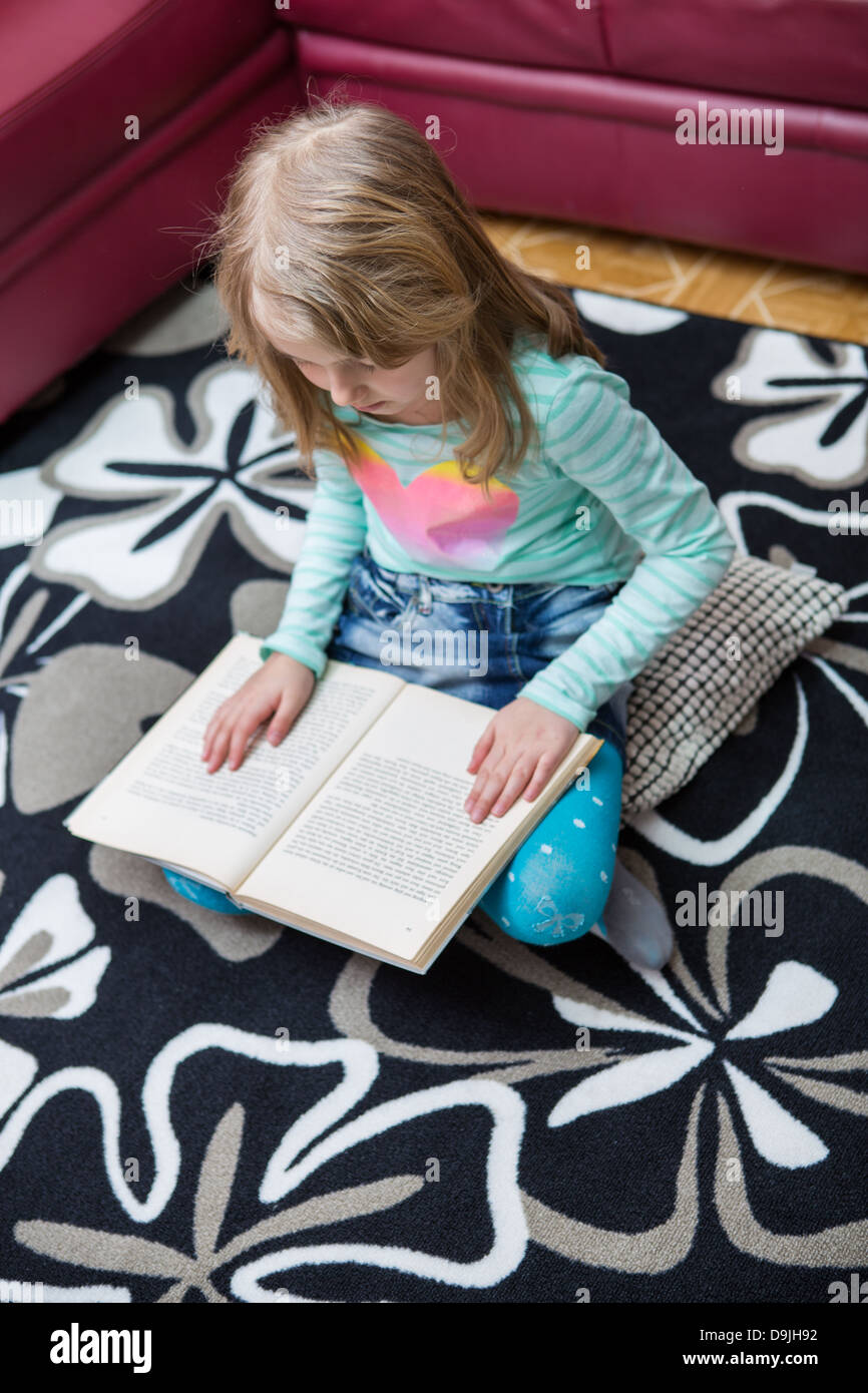 Bambina la lettura di un libro a casa Foto Stock