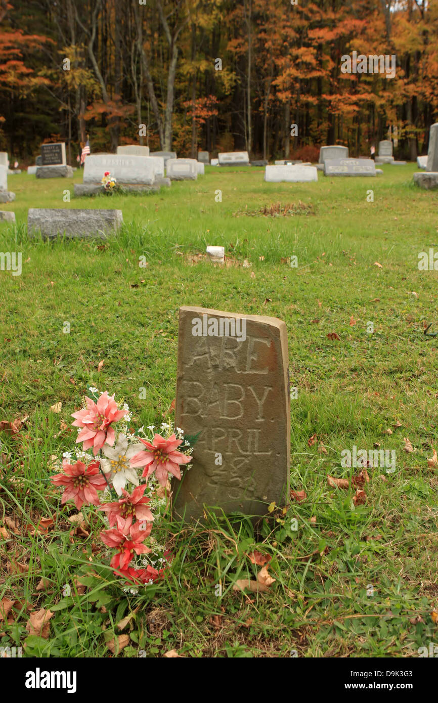 Tomba di pietra lapide marcatore cimitero Baby girl misspell fiori rosa croce autunno autunno erba vecchia 1932 Aprile Foto Stock