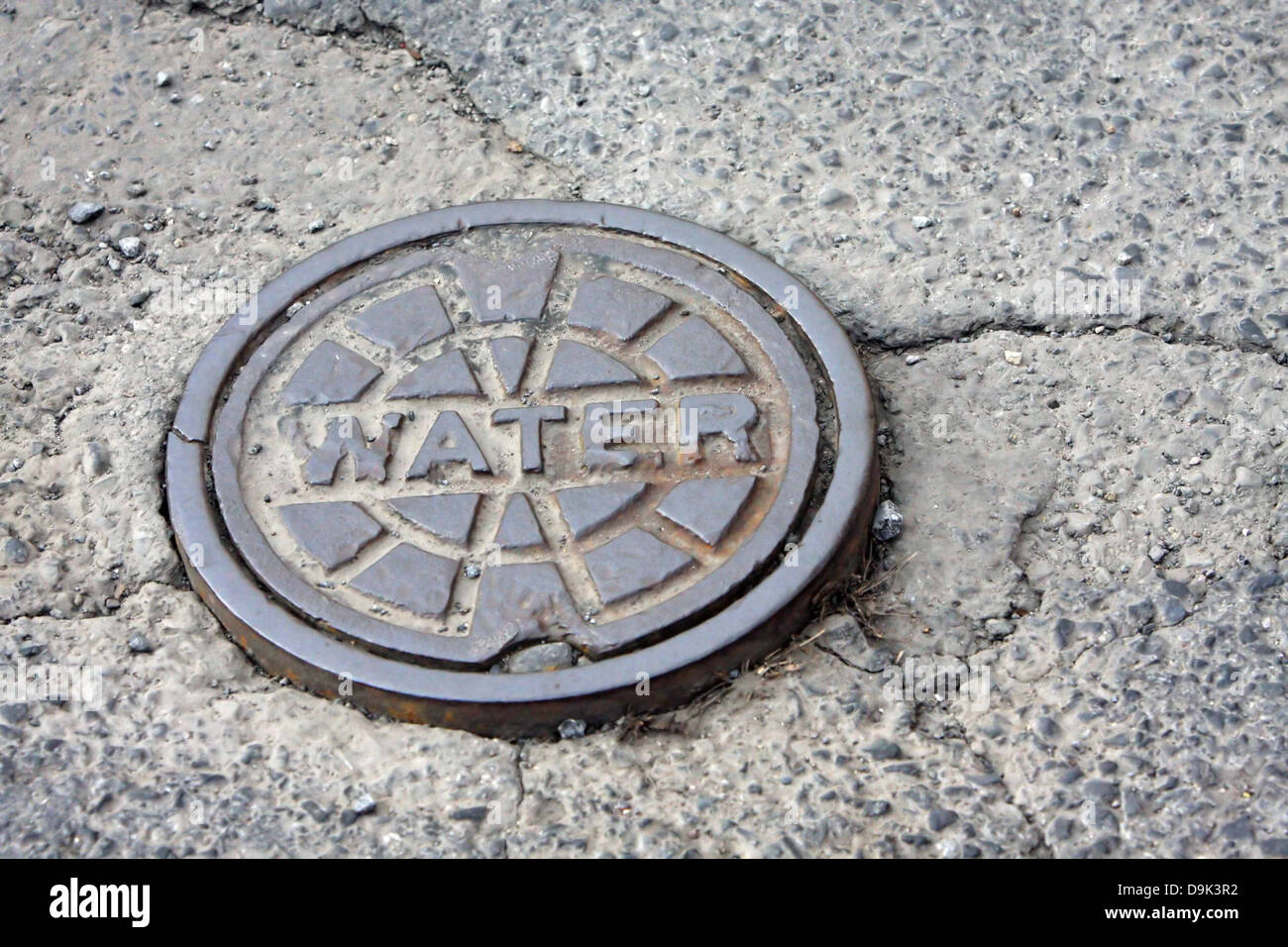 Acqua coperchio di accesso della pavimentazione crepe in calcestruzzo Foto Stock