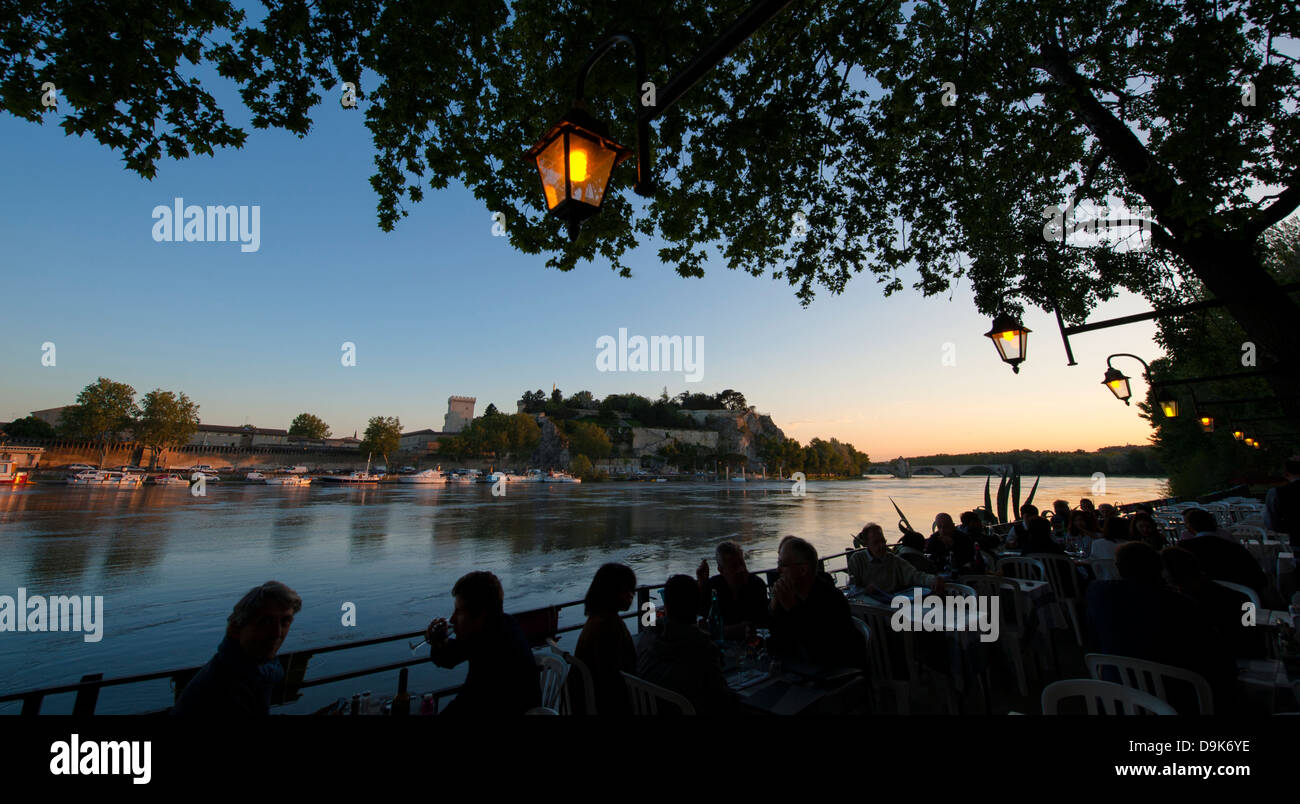 Di sera la vista dal ristorante Le Bercail sulle rive del fiume Rodano con viste su Avignone vecchia, Francia meridionale Foto Stock