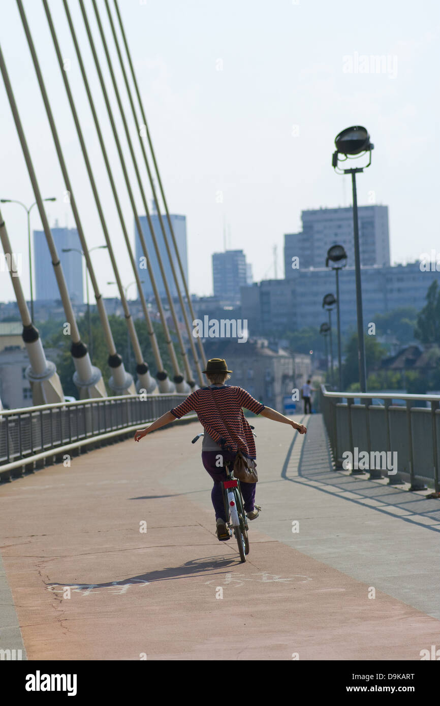 Ciclista in hat con le braccia tese godendo di una corsa sul ponte Świętokrzyski, Varsavia, Polonia Foto Stock