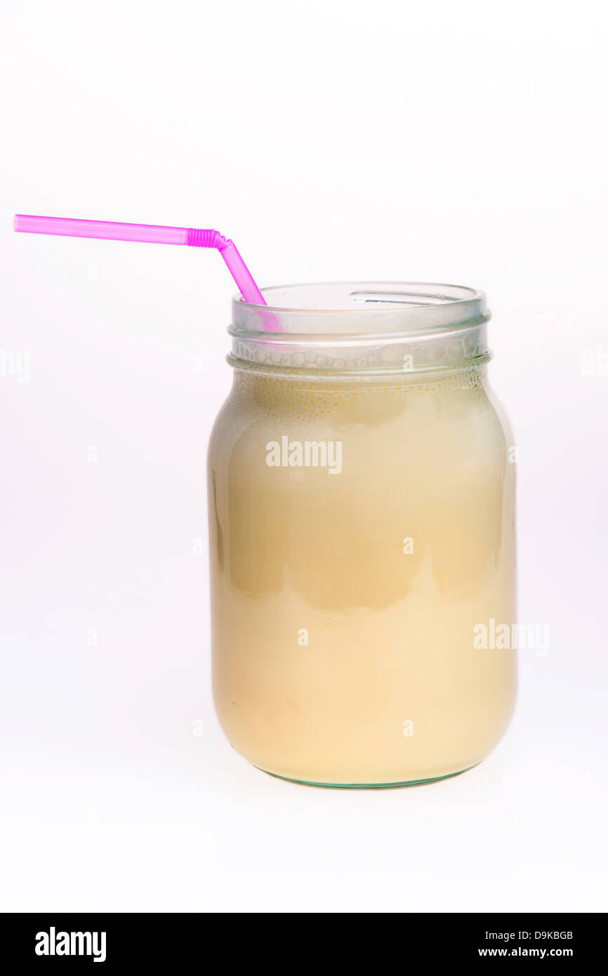 Frullato di banana drink in un vasetto di marmellata con una paglia Foto Stock