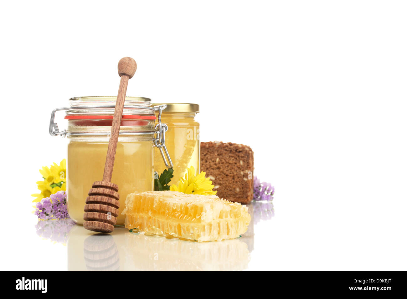 Occhiali di miele di favo di miele, pane integrale, cucchiaio di miele e fiori, vasetti favo di miele, pane integrale, miele e fl Foto Stock