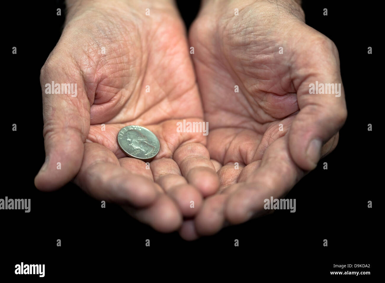 La povertà. Vecchie mani con una singola moneta da 25 centesimi Foto Stock