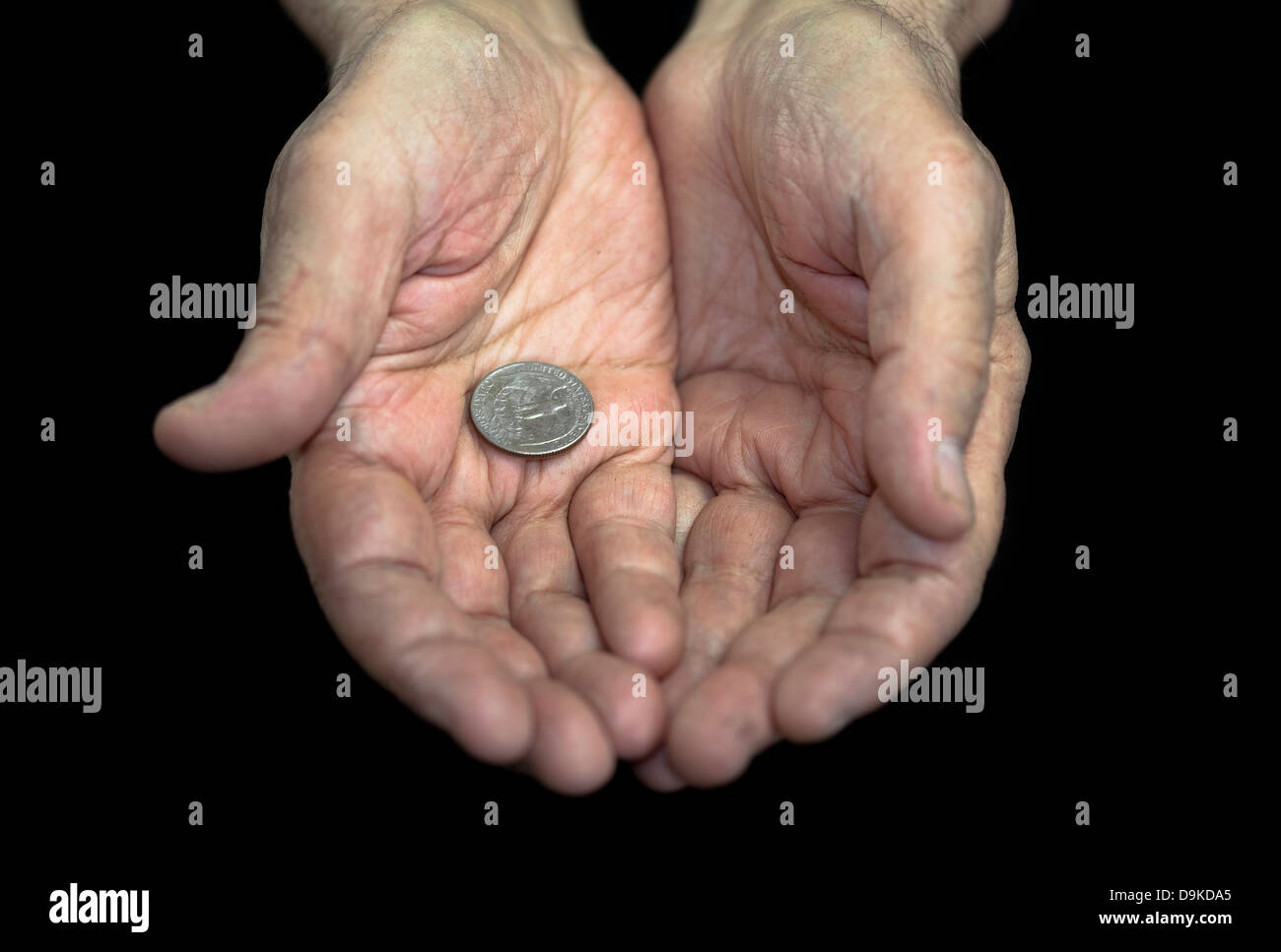 La povertà. Vecchie mani con una singola moneta da 25 centesimi Foto Stock