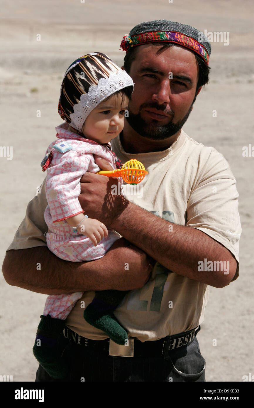 Uomo tagiko tenendo il suo bambino sulle braccia, altopiano del Pamir, Tagikistan Foto Stock