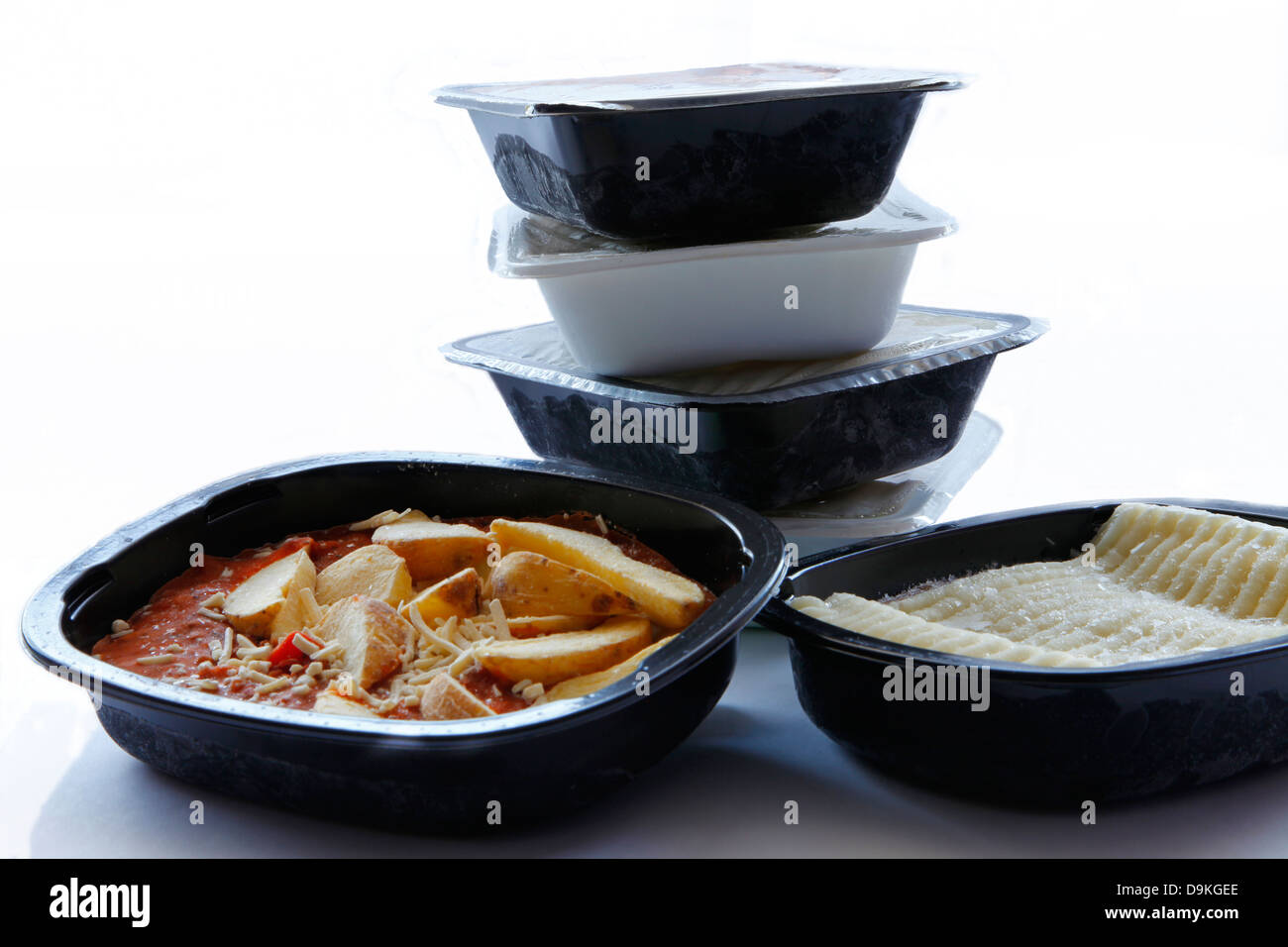 Una vasca di cottage pie e peperoncino chip con una pila di aperti gli alimenti congelati in background Foto Stock