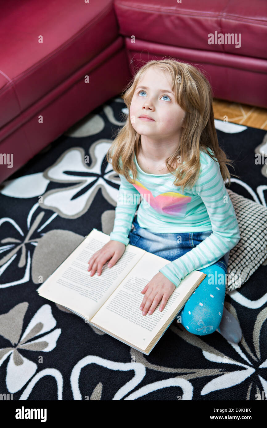 Bambina la lettura di un libro a casa Foto Stock