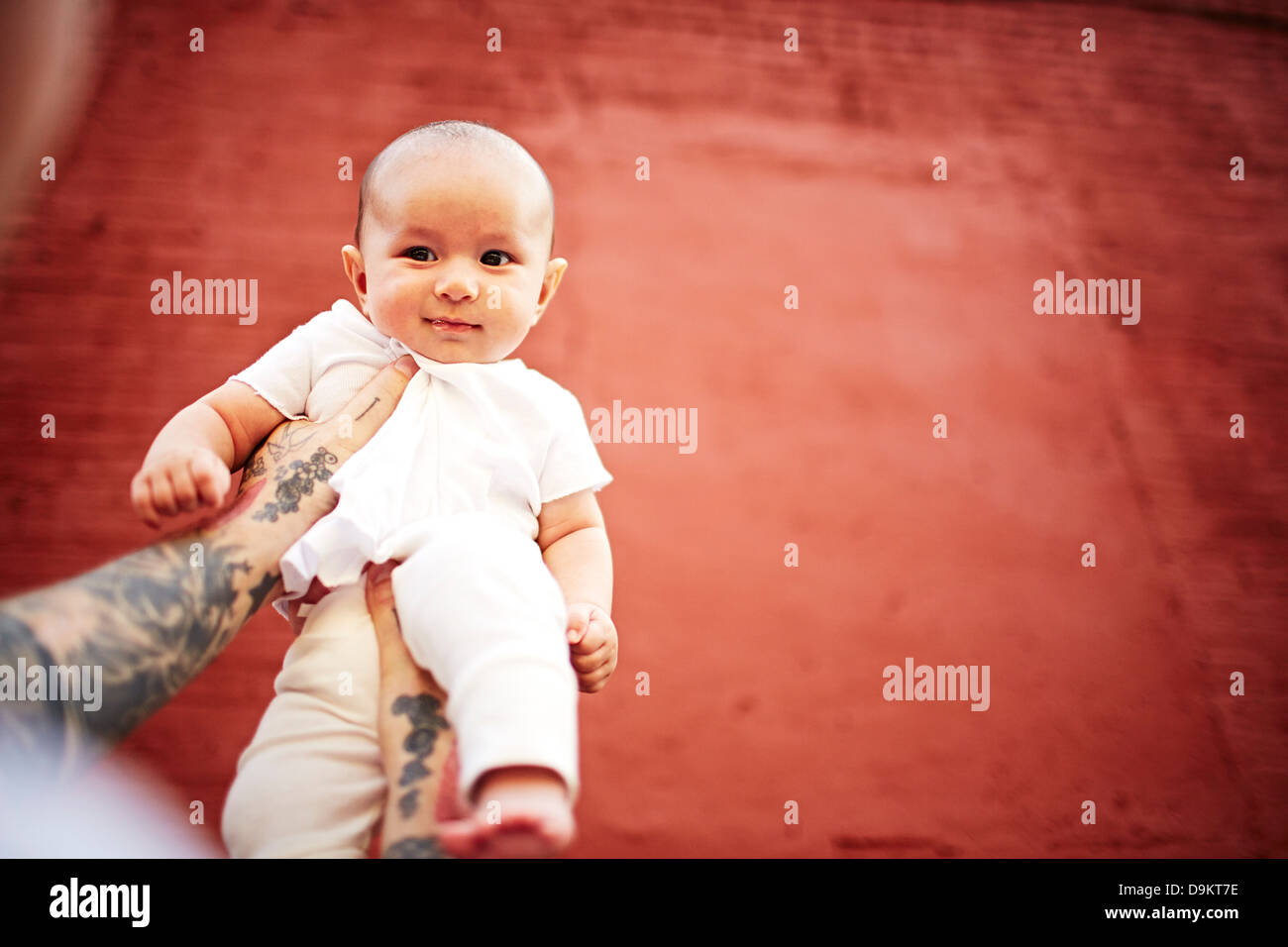Padre holding baby boy contro lo sfondo di colore rosso a basso angolo di visione Foto Stock