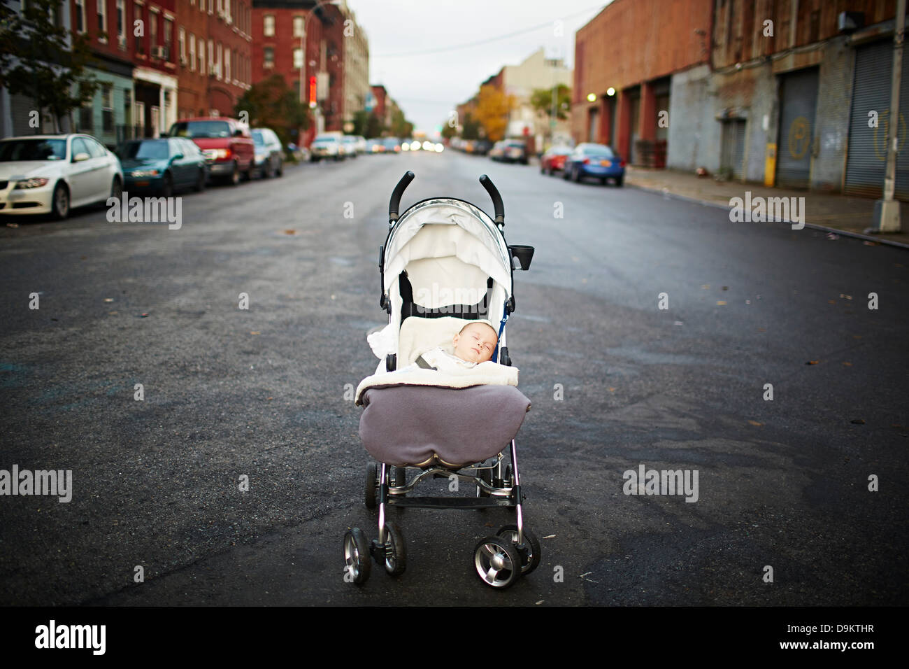 Bambino addormentato in sedia push nel mezzo della strada Foto Stock