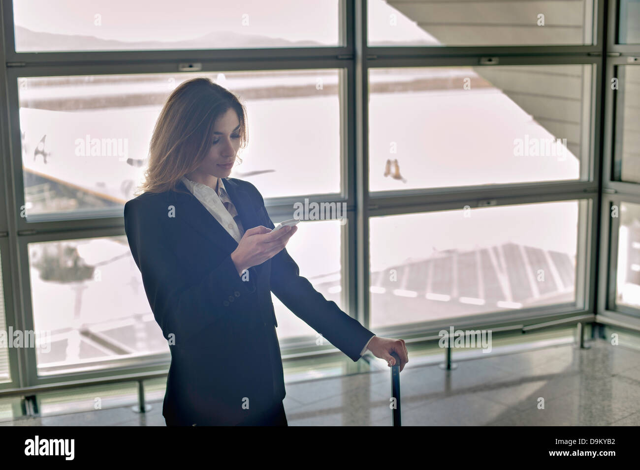 Giovane donna utilizza lo smartphone in aeroporto Foto Stock