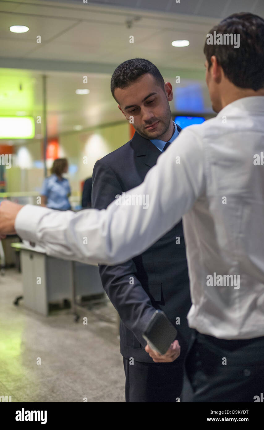 La guardia di sicurezza controllo passeggeri maschi nei controlli di sicurezza in aeroporto Foto Stock