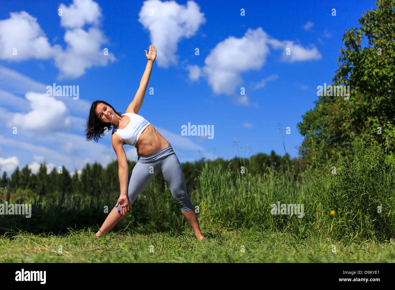 Ragazza fare yoga outdoor cercando nella fotocamera e sorridente, ladscape Foto Stock