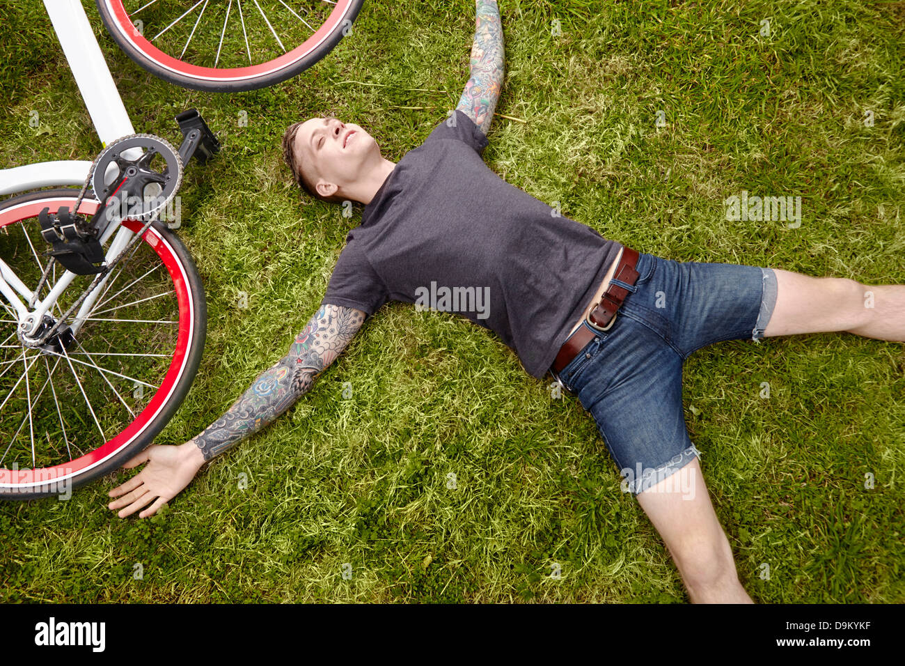 Giovani tatuati uomo disteso sull'erba Foto Stock