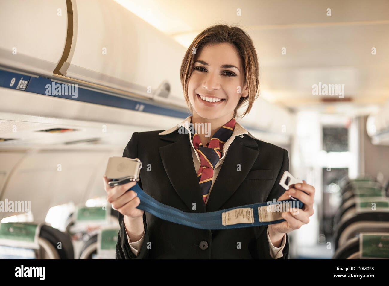 Hostess dell'aria eseguendo la dimostrazione di sicurezza in aereo Foto Stock