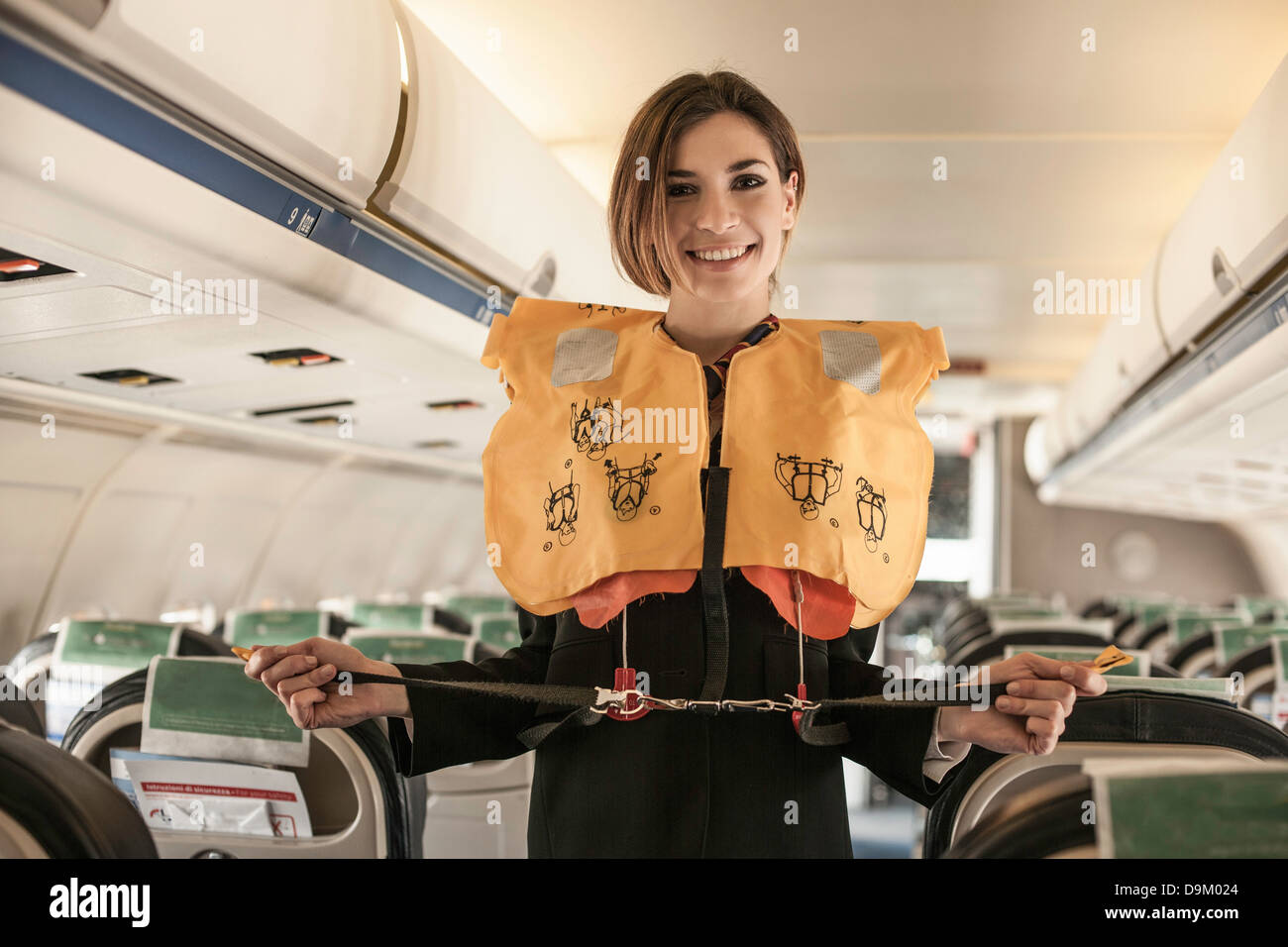 Hostess dell'aria eseguendo la dimostrazione di sicurezza in aereo Foto Stock